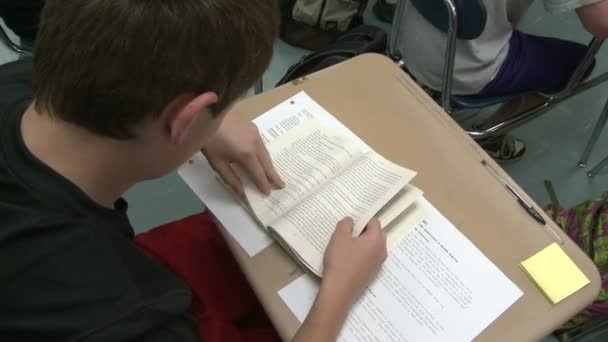 Студент, гортаючи книгу в класі. — стокове відео