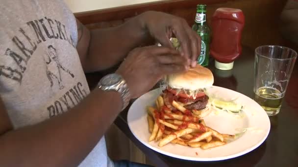 Man eating hamburger with french fries (2 of 2) — Stock Video