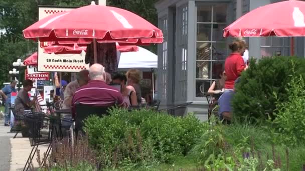People eating under market umbrellas at a sidewalk cafe (3 of 3) — Stock Video