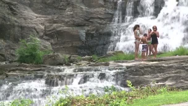 Купальщики, стоящие на дне водопада — стоковое видео