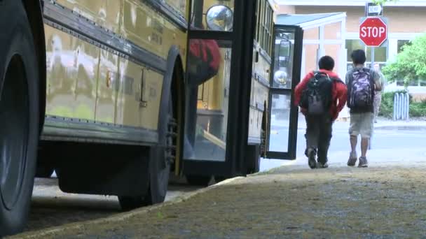 Os rapazes entram no autocarro escolar. — Vídeo de Stock
