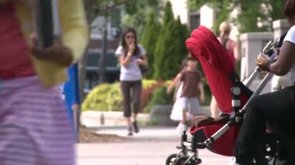Frau mit Kinderwagen sitzt auf Gehwegbank — Stockvideo