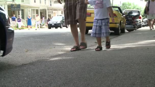 Een man en zijn zoontje wandelen door een geparkeerde auto — Stockvideo