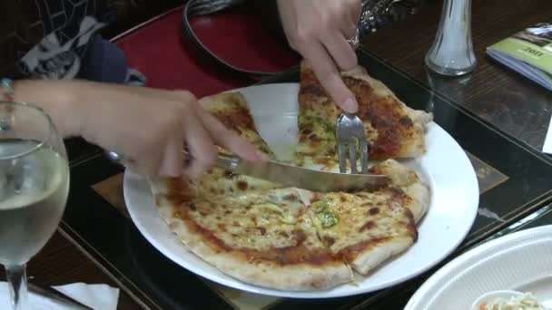 Kvinnan skära en pizza på hennes tallrik — Stockvideo