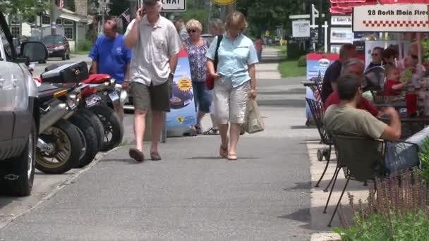 People walking by parked motorcycles along a sidewalk cafe — Stock Video