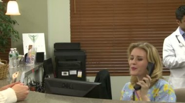 Tipik bir sahne meşgul bir tıbbi uygulama açık resepsiyonist masasında gerçekleşir