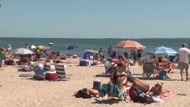 Personas tomando el sol en una playa de arena — Vídeo de stock