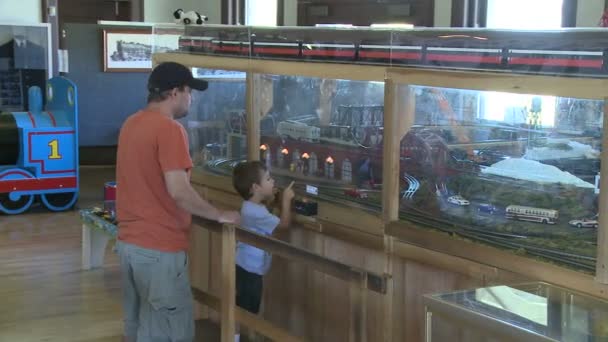 Мужчина и его сын смотрят на модель поезда — стоковое видео