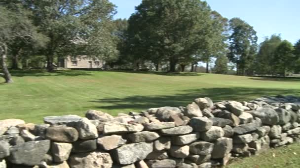 Stone wall around a home with grassy field and trees (1 of 2) — Stock Video