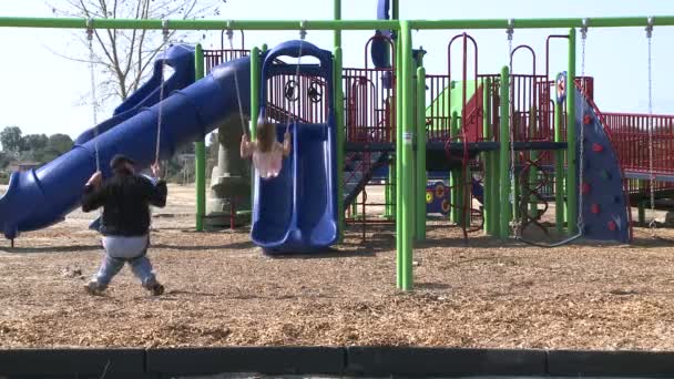 Padre e hija en columpios en el parque infantil — Vídeo de stock