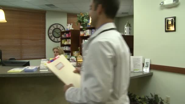 Uma cena típica ocorre na recepção da frente de uma prática médica ocupada — Vídeo de Stock