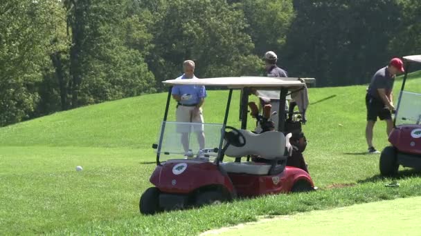 Mężczyzna golfista chodzenie na zielono z wózkiem golfowym zaparkowane (2 z 2) — Wideo stockowe