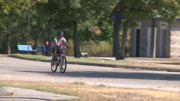Mężczyzna jazdy na rowerze wzdłuż drogi — Wideo stockowe