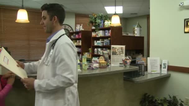 Typická scéna se odehrává na přední recepční stůl rušné lékařské praxe — Stock video