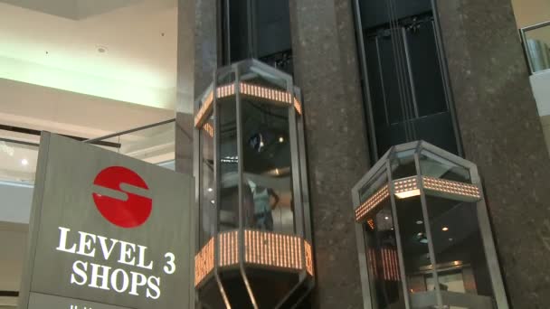 Siguiendo ascensores descendiendo al nivel 3 dentro del centro comercial — Vídeo de stock