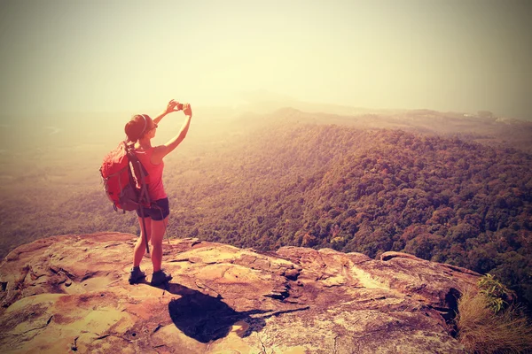 若い女性バックパッカーは 山のピークの上にカメラで写真を撮影 — ストック写真