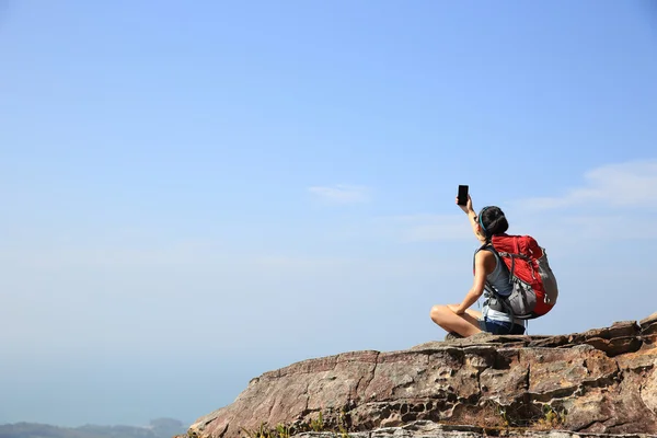 Woman backpacker taking photo on mountain — Stock Photo, Image