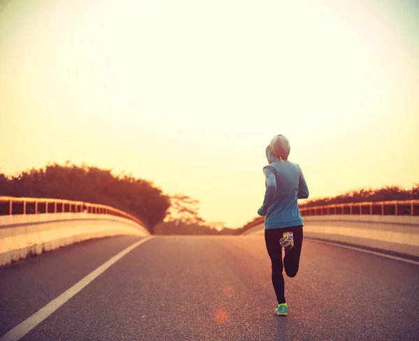 Woman running on sunrise road — Stock Photo, Image