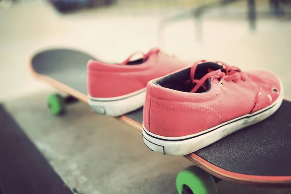 Sneakers and skateboard at skate park — Stock Photo, Image