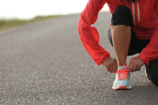 Young woman runner tying shoelace — Stock Photo, Image