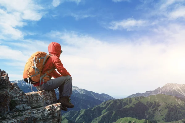 Backpacker sitting on mountain peak — Stock Photo, Image
