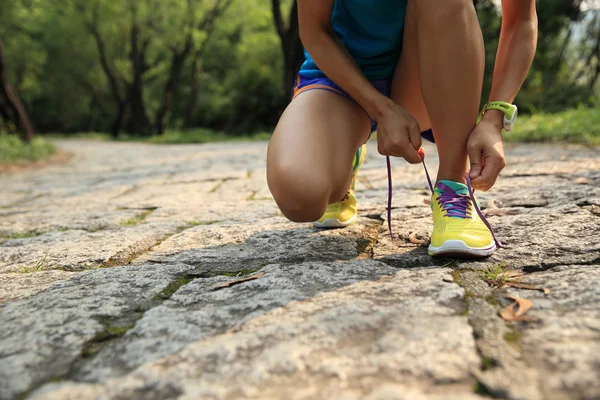 Жінка слідує бігун зав'язуючи шнурки — стокове фото