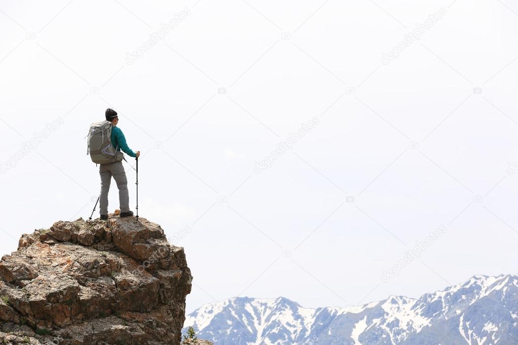 backpacker hiking on mountain peak cliff