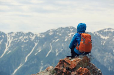 dağ tepe üzerinde oturan backpacker 