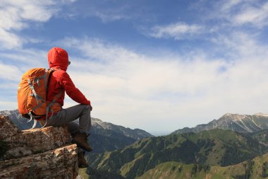 dağ tepe üzerinde oturan backpacker 