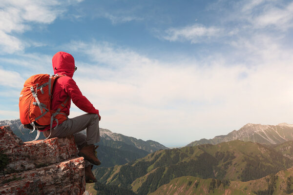 backpacker sitting on mountain peak 