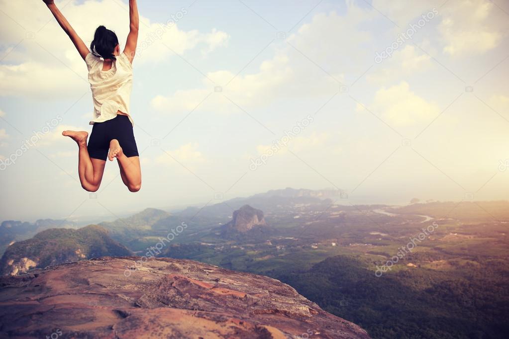 asian woman jumping on mountain peak