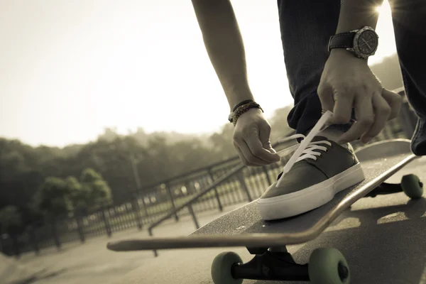 Завязывающий шнурок скейтбордист — стоковое фото