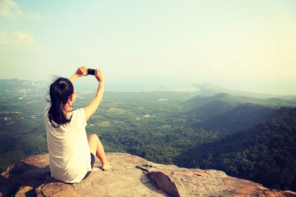 Woman taking photo w at mountain cliff — Stock Photo, Image