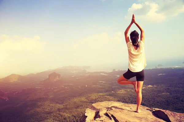 Mujer haciendo yoga en el pico de montaña —  Fotos de Stock