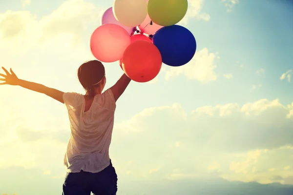 Kvinna på solnedgången med färgade ballonger — Stockfoto