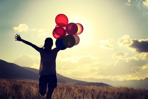 Femme au coucher du soleil avec des ballons colorés — Photo