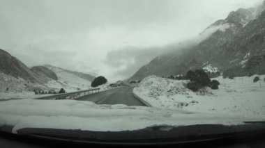 Kış günü karlı dağ yolunda giden off road arabası.