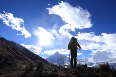 Kış dağlarında yürüyüş yapan bir kadın.