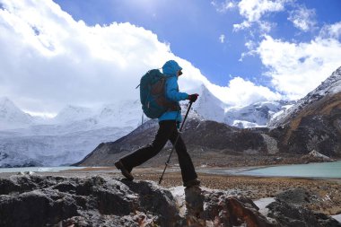 Kış dağlarında yürüyüş yapan bir kadın.