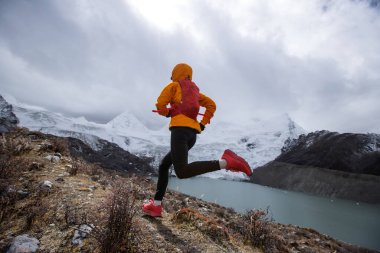 Kadın koşucu kışın dağlarda koşuyor.