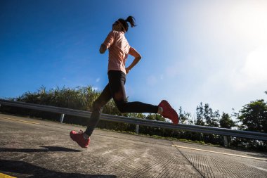 Kadın koşucu kış günü dağın tepesinde koşuyor.