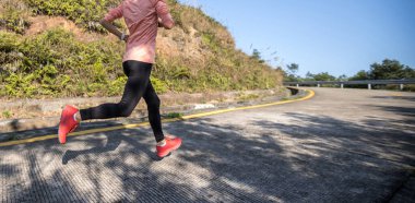 Kadın koşucu kış günü dağın tepesinde koşuyor.