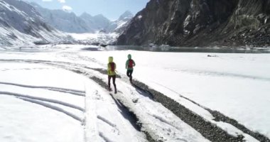 İki kadın, kış doğasında koşan koşucuları takip ediyor. Hava görüntüsü insansız hava aracı görüntüleri yavaş çekimde