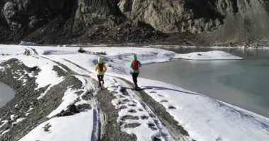 İki kadın, kış doğasında koşan koşucuları takip ediyor. Hava görüntüsü insansız hava aracı görüntüleri yavaş çekimde