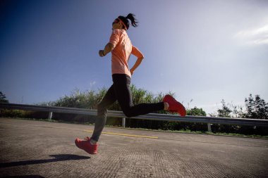 Kadın koşucu kış günü güneşin doğuşunda dağın tepesinde koşuyor.