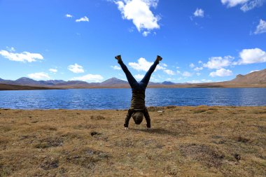 Göl kıyısındaki otlaklarda amuda kalkan insanlar