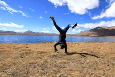Kadın, mavi gökyüzünün altında yüksek irtifada amuda kalkıyor.