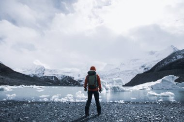 Kış dağlarında yürüyüş yapan bir kadın.