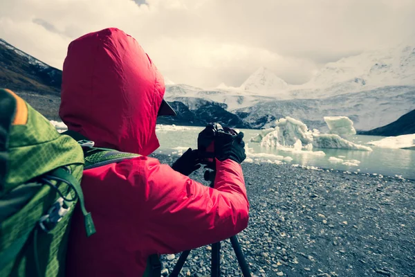 冬の山の中でカメラで写真を撮る女性ハイカー — ストック写真