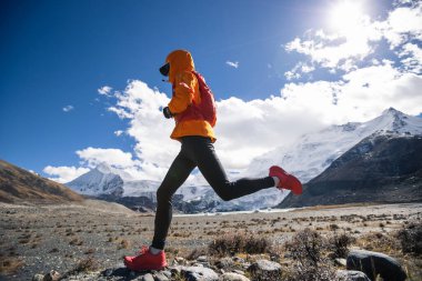 Yüksek irtifada kış mevsiminde koşan kadın koşucu.